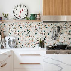 a kitchen with a clock on the wall next to a stove top oven and counter