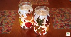 two mason jars sitting on top of a table covered in leaves and acrylic paint