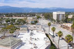 an aerial view of a city street with palm trees and mountains in the back ground