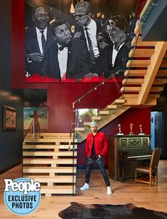 a man standing in front of a staircase next to a wall with pictures on it