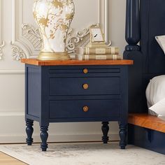 The unmatched style and sophistication of our Repton Blue Two Tone Solid Wood 2 Drawer Bedroom Nightstand will captivate you. Simply, stylish, and timeless, this nightstand enchants with its modern-classic aesthetics. It has been beautifully and skillfully handcrafted from the sturdiest solid wood, so you will be really impressed with its amazing heirloom quality. The design of this solid wood nightstand is incredibly tasteful and dignified. Its extended top frame features a gorgeous rustic grain that contrasts strikingly with the rest of its royal blue finish. The main body consists of one pullout tray at the top where you can keep various food items and stationery when you need extra table space. There are two drawers underneath that, which are spacious enough for you to organize and saf Blue And Black Nightstand, Dark Blue Bedside Cabinets, Dark Blue Bedside Table, Midnight Blue Nightstand, Ornate Nightstand, Bedside Bench, Drawer Bedroom, Wooden Knobs, Wood Bedroom