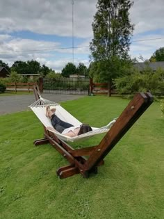 a woman laying in a hammock on top of a green grass covered field