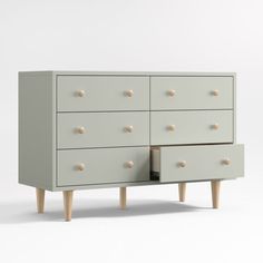 a grey dresser with wooden legs and drawers