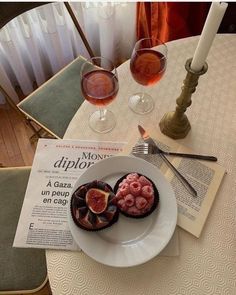 two desserts on a plate with wine glasses in the background and a menu for an appetizer