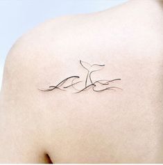 the back of a woman's shoulder with a bird tattoo on her left side