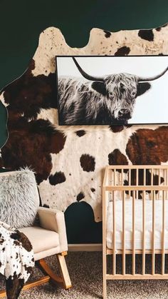 a baby's room with a cow painting on the wall and a rocking chair