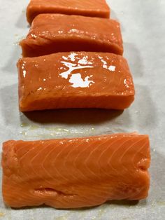 three pieces of raw salmon sitting on wax paper