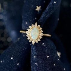 an opal and diamond ring on top of a blue cloth with stars in the background