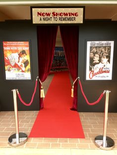 a red carpeted entrance to a movie theater with posters on the wall behind it