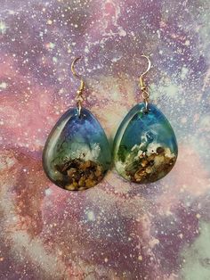 pair of earrings with blue and green glass tears on space background, closeup