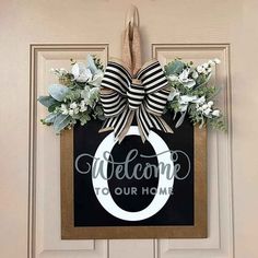 welcome to our home door hanger with flowers and ribbon on the front door frame