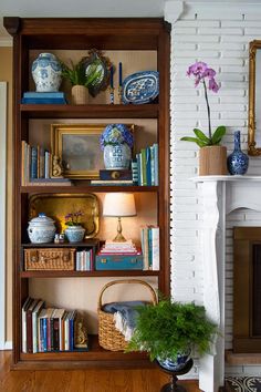 a bookshelf filled with lots of books next to a fireplace