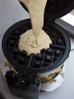 a waffle being drizzled with icing from a pancake maker