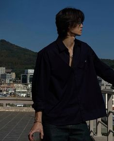 a man standing on top of a roof with his hand in the air and buildings behind him