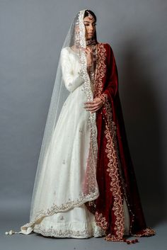 a woman in a white and red wedding dress standing next to a man wearing a veil