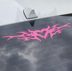 a pink sticker on the side of a white car that has flames painted on it