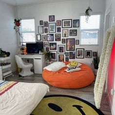 a bedroom with an orange bean bag chair in front of a computer desk and various pictures on the wall