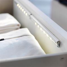 an open drawer with folded white sheets and zippers on the bottom, in front of a mirror