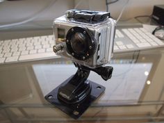 a small camera sitting on top of a glass table next to a keyboard and mouse