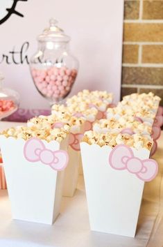 pink and white popcorn boxes with bows on them at a minnie mouse birthday party or baby shower