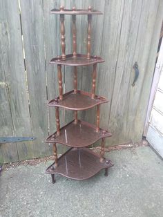 three tiered wooden shelf sitting on top of a cement floor next to a fence