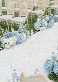 an outdoor wedding setup with blue and white flowers on the aisle, along with chairs