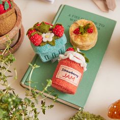 there are two small cakes on top of a book with strawberries and jam in the jar