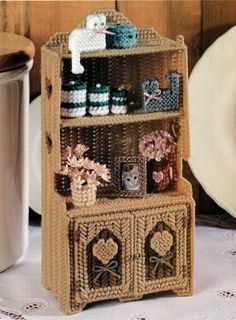 a wicker shelf with baskets and jars on it next to a white table cloth