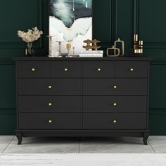 a black dresser with gold knobs in front of a green wall and white floor