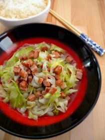 a black plate topped with lettuce and bacon next to a bowl of rice