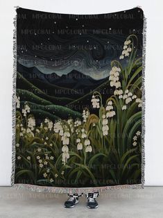 a large tapestry with white flowers and mountains in the background, hanging on a wall