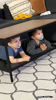 two young boys laying on the floor in a coffee table