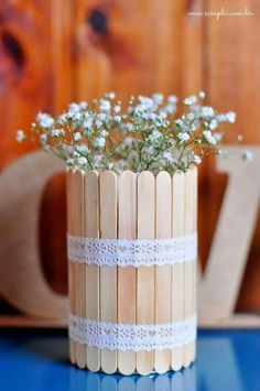 a wooden vase with white flowers in it sitting on a blue table next to a wall