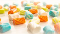 there are many different colored candies on the table, one is white and orange