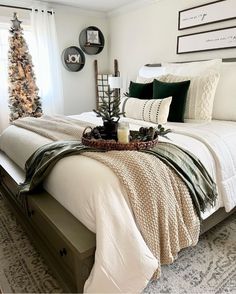 a white bed topped with pillows and blankets next to a window covered in christmas decorations