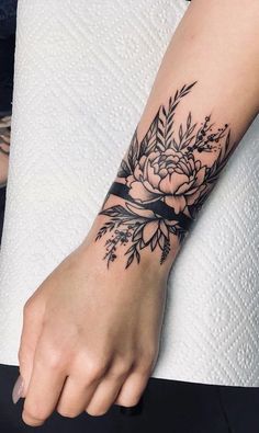 a woman's hand with a flower tattoo on her left wrist and the other arm