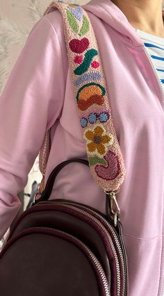 a woman wearing a pink hoodie and carrying a brown purse with flowers on it