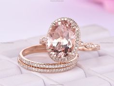 an oval cut morganite and diamond ring set on top of a white box with pink flowers in the background