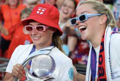 two women in red hats and sunglasses are smiling at the camera while others watch from behind them