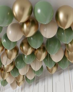 many green and gold balloons hanging from the ceiling