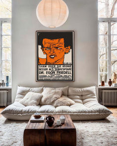 a living room with a couch, coffee table and large poster hanging on the wall