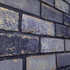 an old brick wall that has been painted blue and yellow with some rust on it