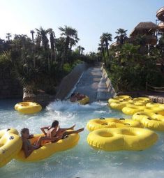 two people on inflatable rafts ride down the water slide at an amusement park