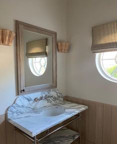 a bathroom with marble counter top and two round windows