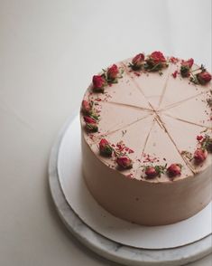 a white cake with pink frosting and strawberries on top sitting on a plate