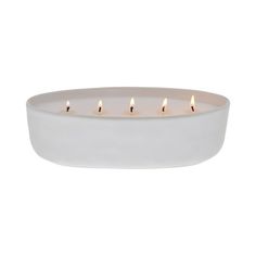 a white bowl with five lit candles in it