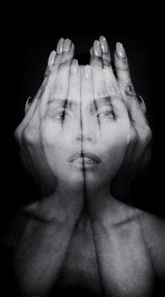 a black and white photo of a woman's face with hands covering her eyes