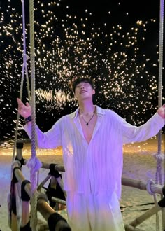 a man standing on a swing with fireworks in the background