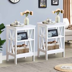 two white side tables with baskets on them in front of a blue wall and clock