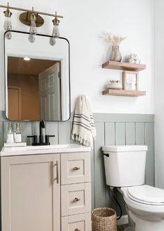 a white toilet sitting next to a sink in a bathroom under a mirror and lights